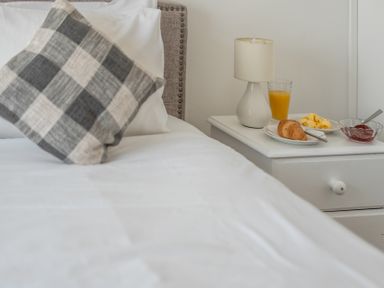A bedroom with a pillow and breakfast items on a nightstand at The Lookout in Sennen