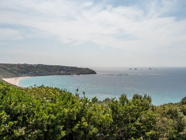 A view of a beach and ocean with cliffs and houses at The Lookout in Sennen