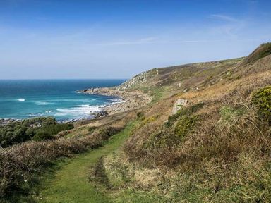 A coastal path with grass and shrubs overlooking the sea at The Coach House in Sennen near St Just