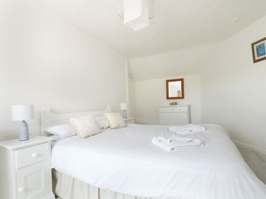 A bedroom with a double bed two bedside tables with lamps a chest of drawers and a mirror at The Coach House in Sennen near St Just