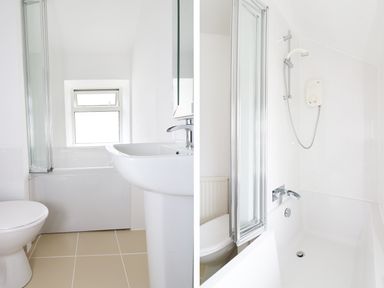 A bathroom with a toilet, pedestal sink, bathtub with showerhead, and a frosted window at The Coach House in Sennen near St Just