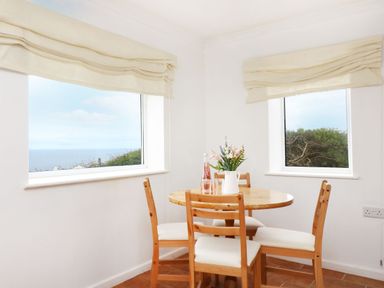 A dining room with a round table and chairs at The Coach House in Sennen near St Just