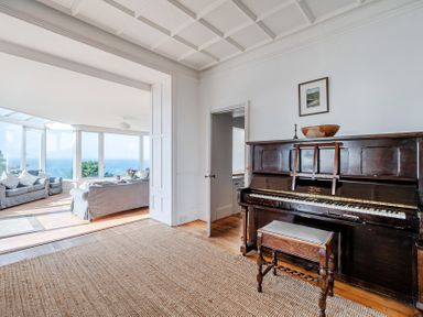 A living room with a piano and a doorway at Carn Eve in Sennen Cove near St Just