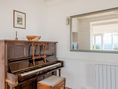 A living room with a piano and a mirror at Carn Eve Sennen Cove near St Just