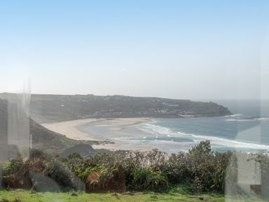 A view of a beach with shoreline and cliffs at Carn Eve in Sennen Cove near St Just