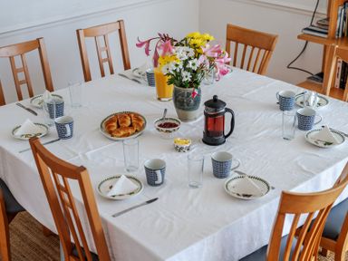 A dining room table set with croissants and drinks at Carn Eve Sennen Cove near St Just