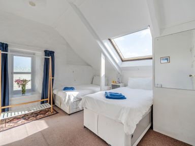 A bedroom with two beds and a window at Carn Eve in Sennen Cove near St Just