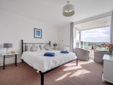A bedroom with a bed and seats by the window at Carn Eve Sennen Cove near St Just