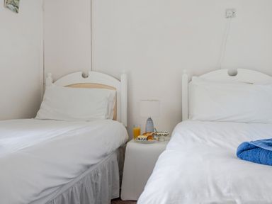 A bedroom with two beds and a bedside table at Carn Eve Sennen Cove near St Just