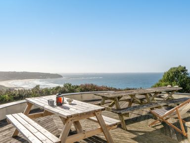 An outdoor seating area with a table and chairs overlooking the ocean at Carn Eve in Sennen Cove near St Just