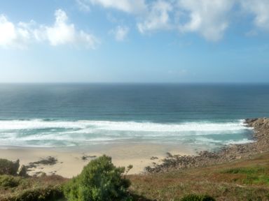 A view of the ocean with sand and rocks at Carn Eve Sennen Cove near St Just