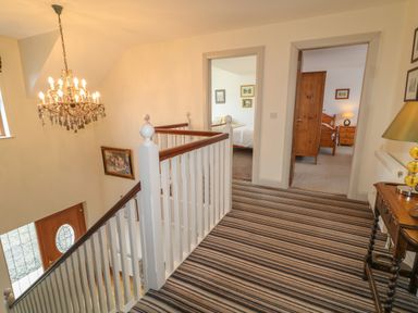 A hallway with striped carpet and a chandelier above the stairs at Millers Lane House in Muff County Donegal
