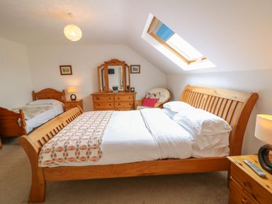 A bedroom with a double bed and a single bed a dresser with a mirror a chair and a skylight at Millers Lane House in Muff County Donegal