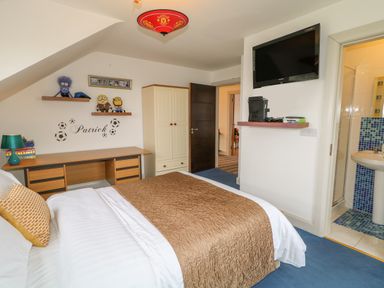 A bedroom with a bed desk wardrobe and television at Millers Lane House in Muff County Donegal