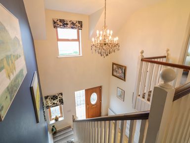 A staircase with a wooden door window and chandelier at Millers Lane House in Muff County Donegal