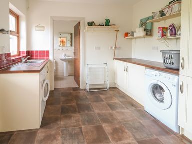 A utility room with washing machines cabinets and shelves at Millers Lane House in Muff County Donegal