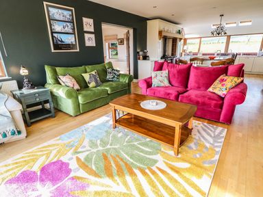 A living room with green and pink sofas a wooden coffee table and a colorful floral rug at Millers Lane House in Muff County Donegal