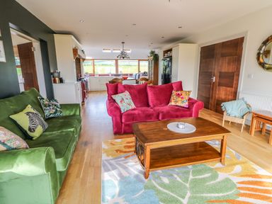 A living room with green and red sofas a wooden coffee table and a colorful rug at Millers Lane House in Muff County Donegal