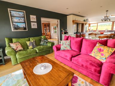 A living room with green and pink sofas and a wooden coffee table at Millers Lane House Muff County Donegal