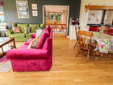 A living room with green and pink sofas and wooden dining table at Millers Lane House in Muff County Donegal