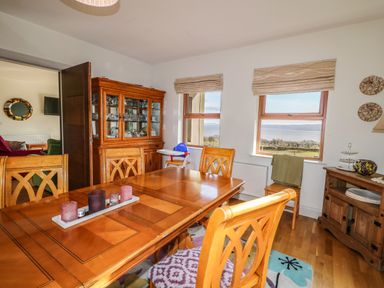 A dining room with wooden table and chairs two windows with landscape view at Millers Lane House in Muff County Donegal