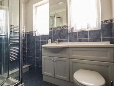 A bathroom with a shower enclosure sink cabinet toilet and windows at Skylark in Weybourne