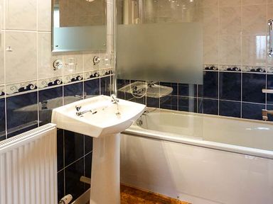 A bathroom with a sink and bathtub with a glass shower screen at Pine Lodge in Culbokie