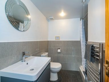 A bathroom with a sink toilet mirror shower and towel rack at Penbarden Barn in Dizzard near Crackington Haven
