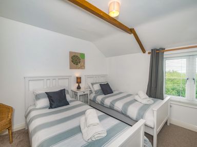 A bedroom with two single beds with striped bedding and a nightstand in between at Penbarden Barn in Dizzard near Crackington Haven