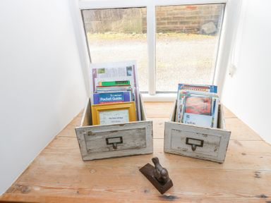 Two wooden boxes with brochures and guides on a windowsill with a bird-shaped doorstop at The Dale Cottage in Allendale near Hexham