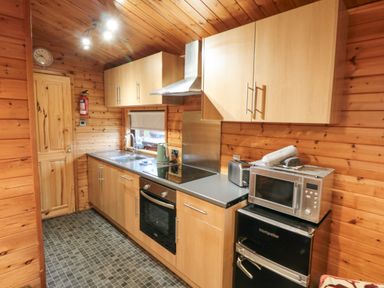 A kitchen with wooden cabinets a microwave toaster oven sink and electric stove at Sycamore Lodge in Liverton near Danby