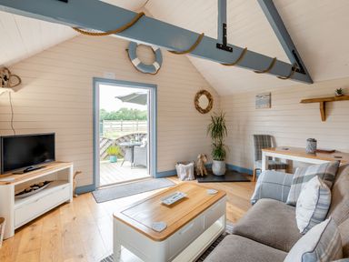A living room with a sofa and coffee table a television on a stand and a dining table with chairs at The Nook in Louth