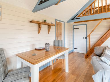 A dining area with a wooden table and gray plaid chairs near a wooden door and staircase at The Nook in Louth