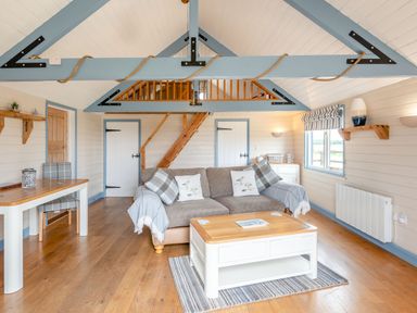A living room with a sofa pillows coffee table wooden floor and exposed beams at The Nook in Louth