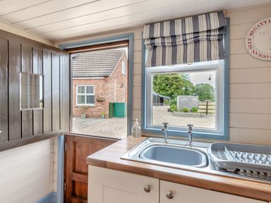 A kitchen sink with dish rack and window with striped blind above at The Nook in Louth