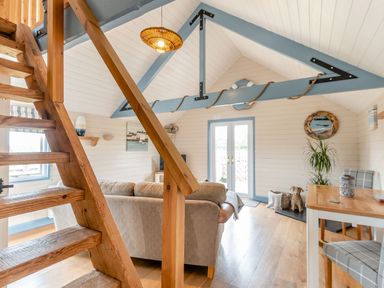A living room with a wooden staircase a sofa a wooden dining table with chairs and French doors at The Nook in Louth