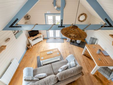 A living room with a sofa, coffee table, dining table with chairs, TV on a stand, and wooden floors at The Nook in Louth