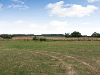 A grassy field with a wooden frame in the middle and a fence in the background at The Nook in Louth