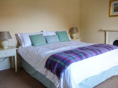 A bedroom with a double bed green pillows bedside tables with lamps and a fireplace at Woodside Cottage Brompton-by-Sawdon