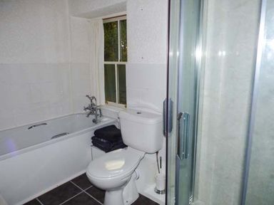 A bathroom with a bathtub, toilet, shower enclosure, and a window at Woodside Cottage in Brompton-by-Sawdon