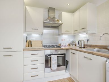 A kitchen with white cabinets wooden countertops a gas stove a kettle and a sink at Kymin View in Monmouth