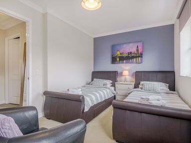 A bedroom with two single beds a nightstand with a lamp and a painting above at Kymin View in Monmouth
