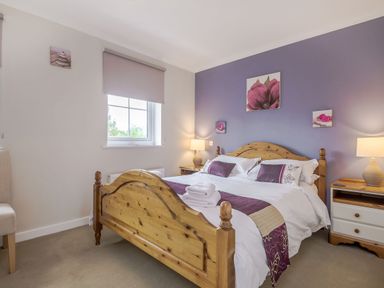 A bedroom with a wooden bed and bedside tables with lamps at Kymin View in Monmouth