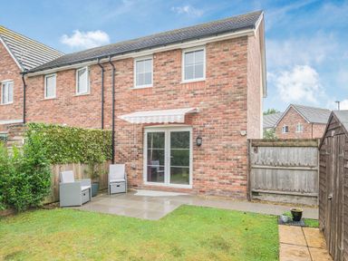 A small garden with two chairs a retractable awning and patio doors at Kymin View in Monmouth
