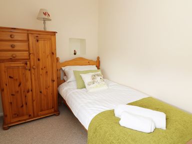 A bedroom with a single bed a wooden wardrobe and a lamp on top at Dolau Farmhouse in Lampeter