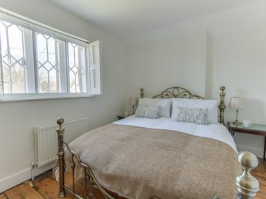 A bedroom with a metal bed frame bedside tables lamps and a window at The Old School House in Piddletrenthide