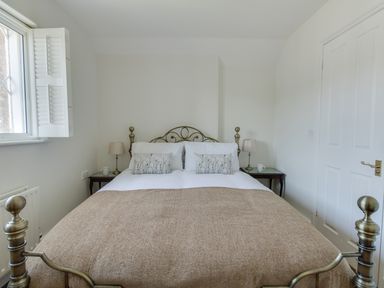A bedroom with a double bed two bedside tables with lamps cups and a window at The Old School House in Piddletrenthide