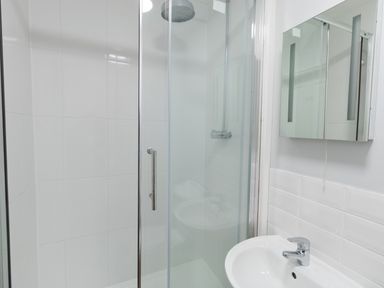 A bathroom with a glass shower enclosure a white sink and a mirrored cabinet at The Old School House in Piddletrenthide