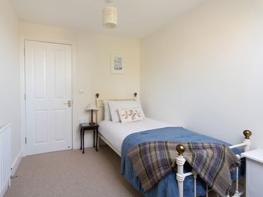 A bedroom with a single bed table lamp and framed artwork at The Old School House in Piddletrenthide