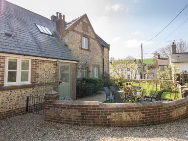 An outdoor patio area with a table and chairs and a brick wall in front of a stone and brick house at The Old School House in Piddletrenthide